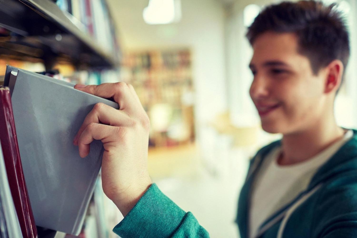 Young student picking a book from a library shelf during a reading club
